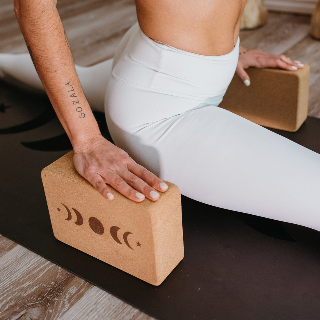 Cinturón de 2m y dos bloques Moon de Sukha Argentina para yoga, en color gris y en uso sobre una esterilla blanca.