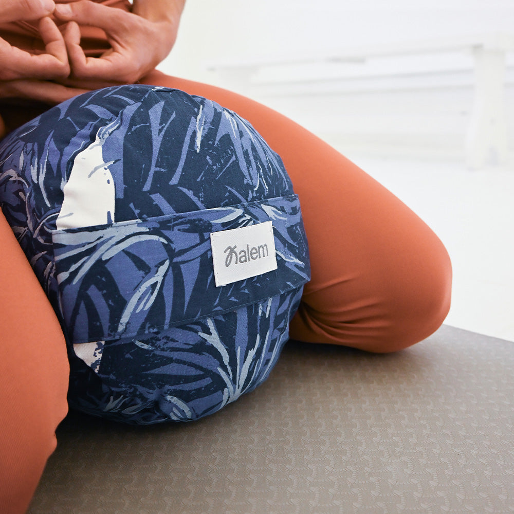 Rollo de yoga redondo estampado en colores vibrantes con relleno de estopa, ideal para prácticas de yoga y meditación.