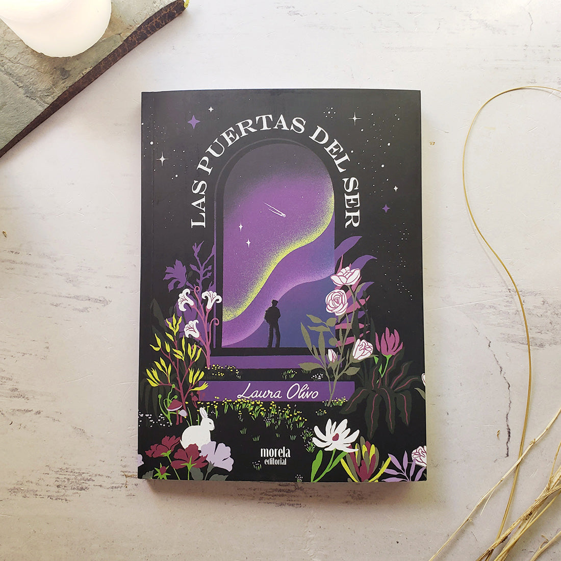 Libro Sukha Argentina "Las puertas del ser" abierto, con páginas blancas y texto en la portada, en una mesa de madera.