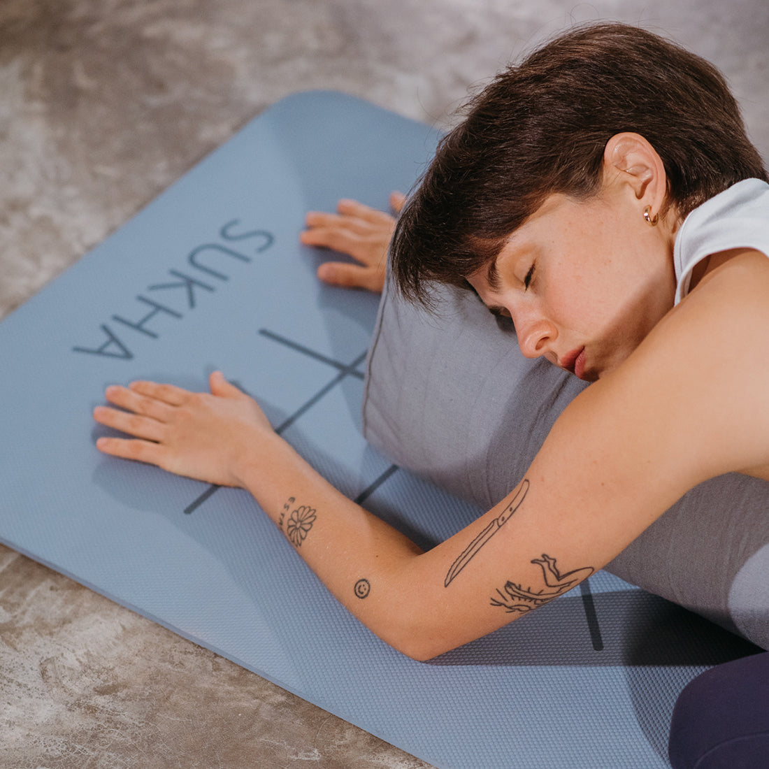 Bolster rectangular gris de Sukha Argentina para yoga, visible en la imagen, ideal para soporte y comodidad en prácticas de yoga.